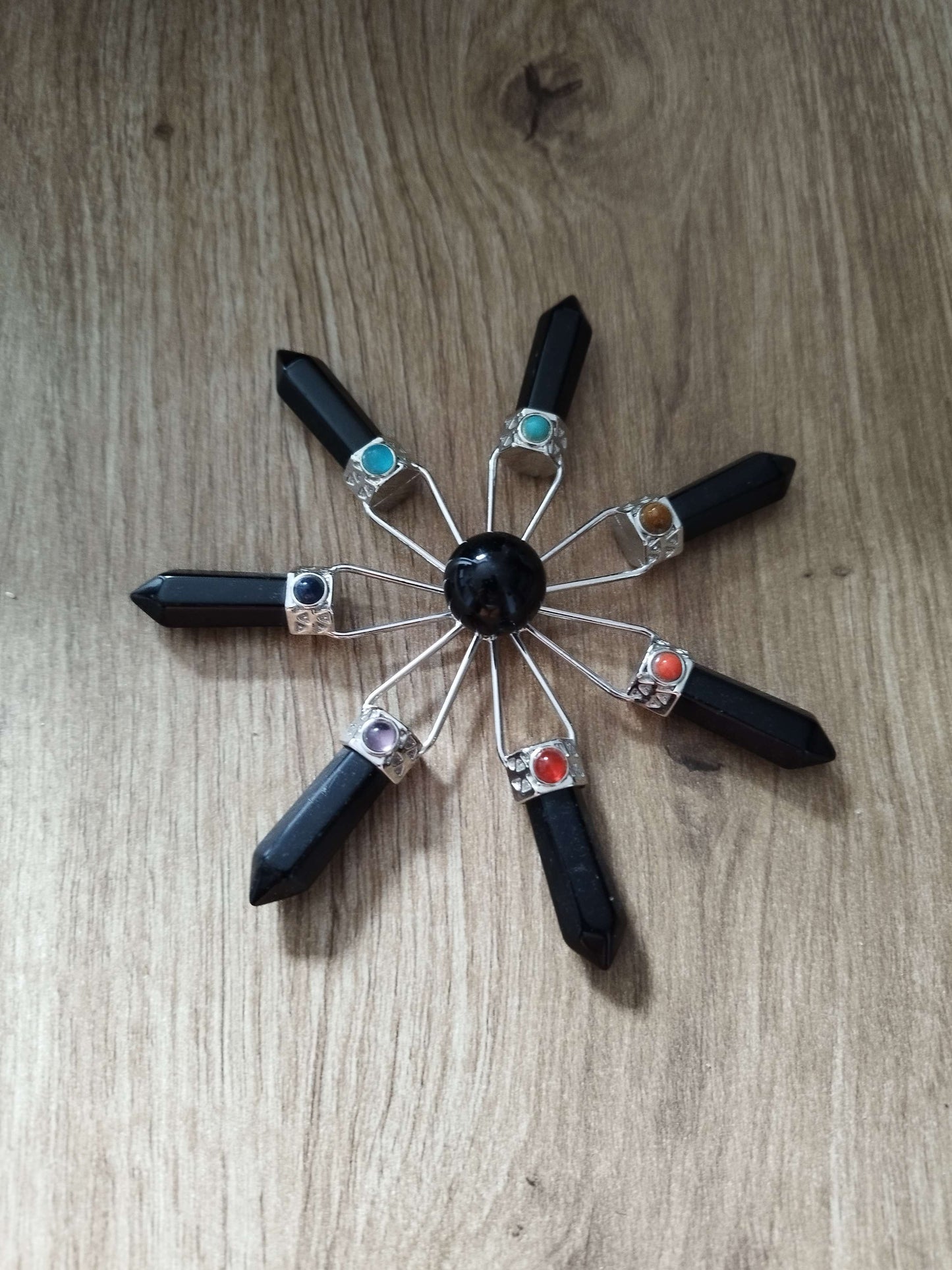 Étoile de guérison Atlante en pierres noires avec cabochons chakras, posée sur une surface boisée naturelle – outil vibratoire de protection et d'harmonisation énergétique